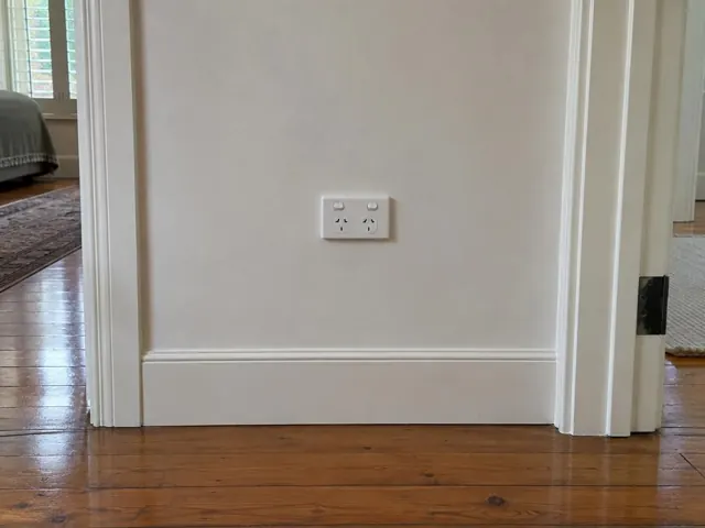 White double power point on a painted hallway wall with timber trim and floorboards in Kensington