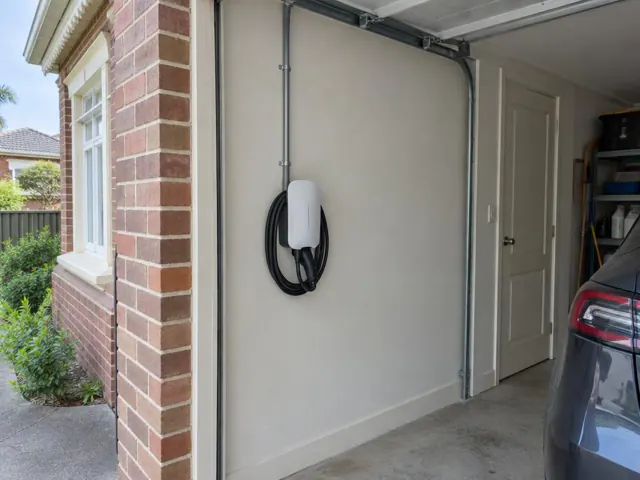 Wall-mounted EV charger beside a garage door in a brick home garage in Maroubra