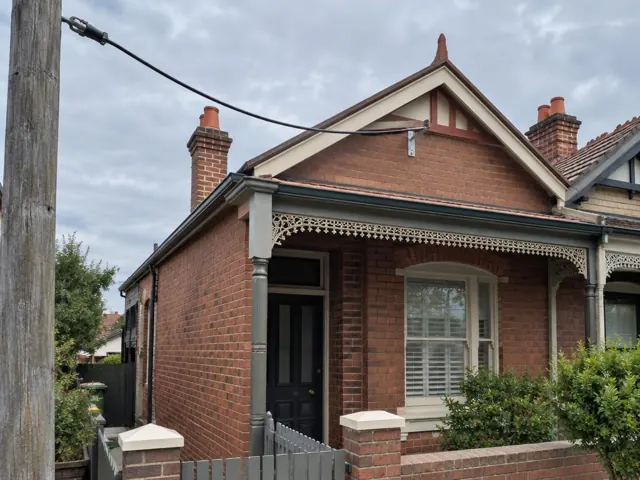 Brick house exterior with overhead service cable and new attachment bracket on the gable in Randwick