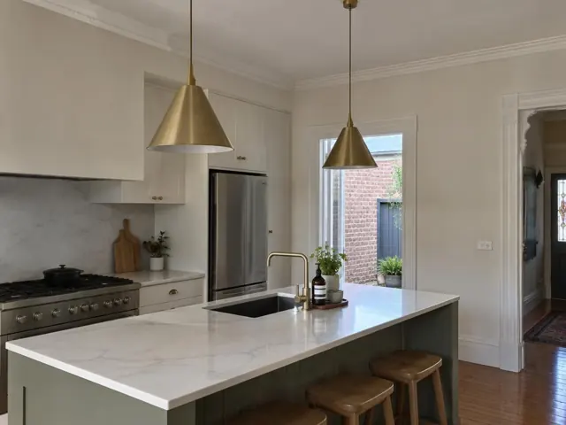Modern kitchen with brass pendant lights over a marble island and timber stools in Randwick